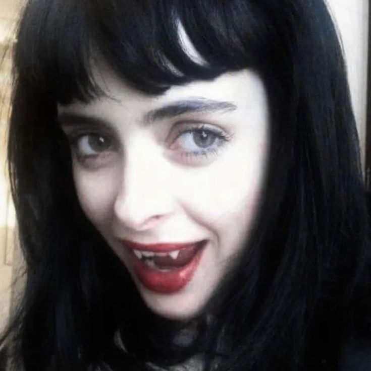 a close up of a person with long black hair and red lipstick on her face