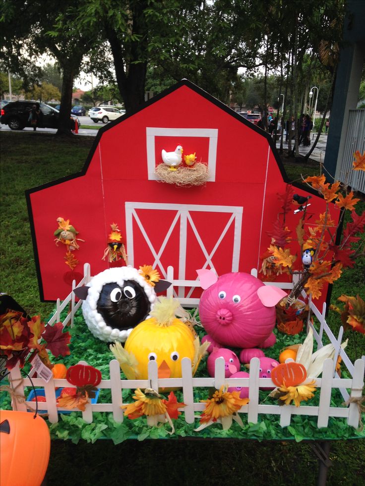 an outdoor display with farm animals and pumpkins on the grass near a red barn