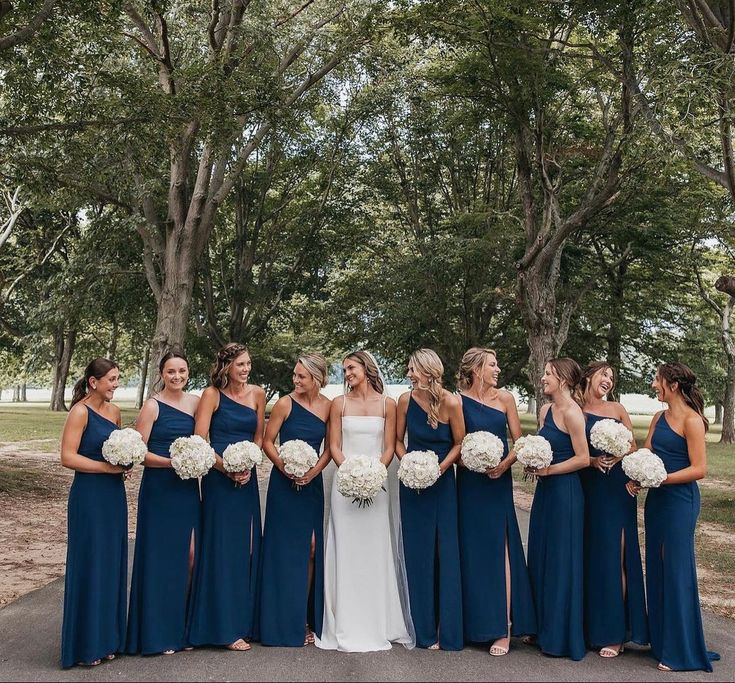 a group of women standing next to each other holding bouquets in their hands and posing for the camera