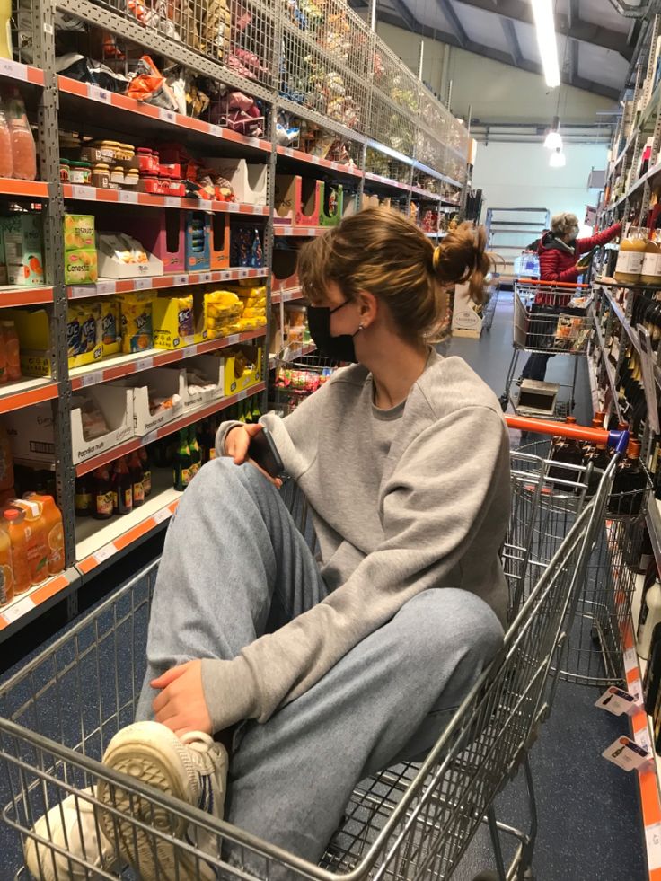 a woman sitting in a shopping cart at a grocery store