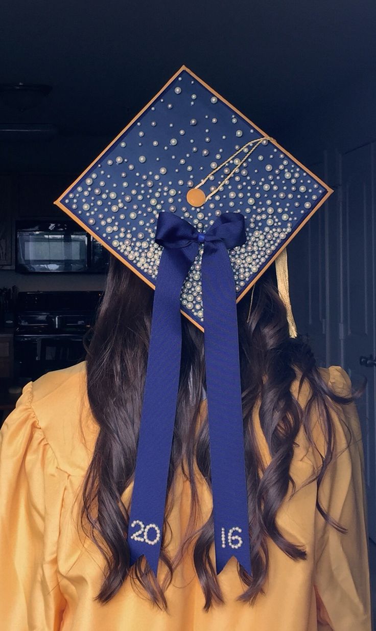 a woman wearing a blue graduation cap with stars on it's side and a ribbon tied around her head