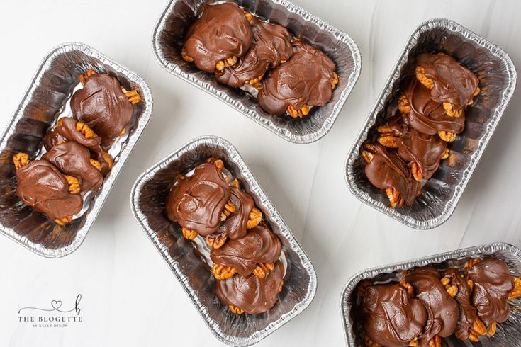 four plastic trays filled with chocolate and nuts on top of a white countertop