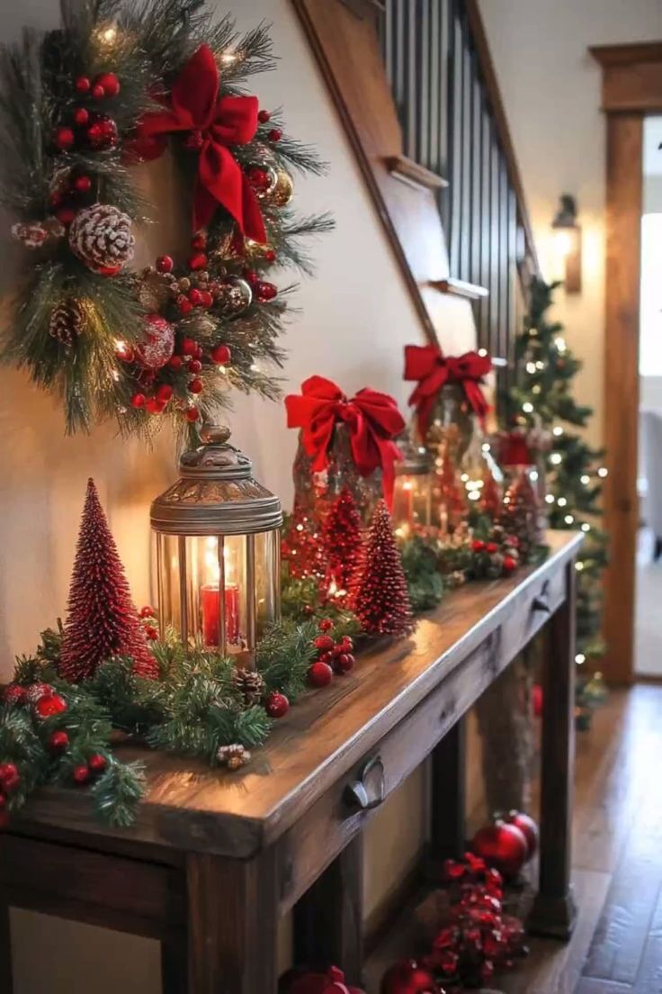 christmas decorations on a table in front of a staircase with red and green garlands