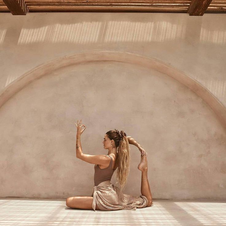 a woman is sitting on the floor with her hands up in the air while stretching