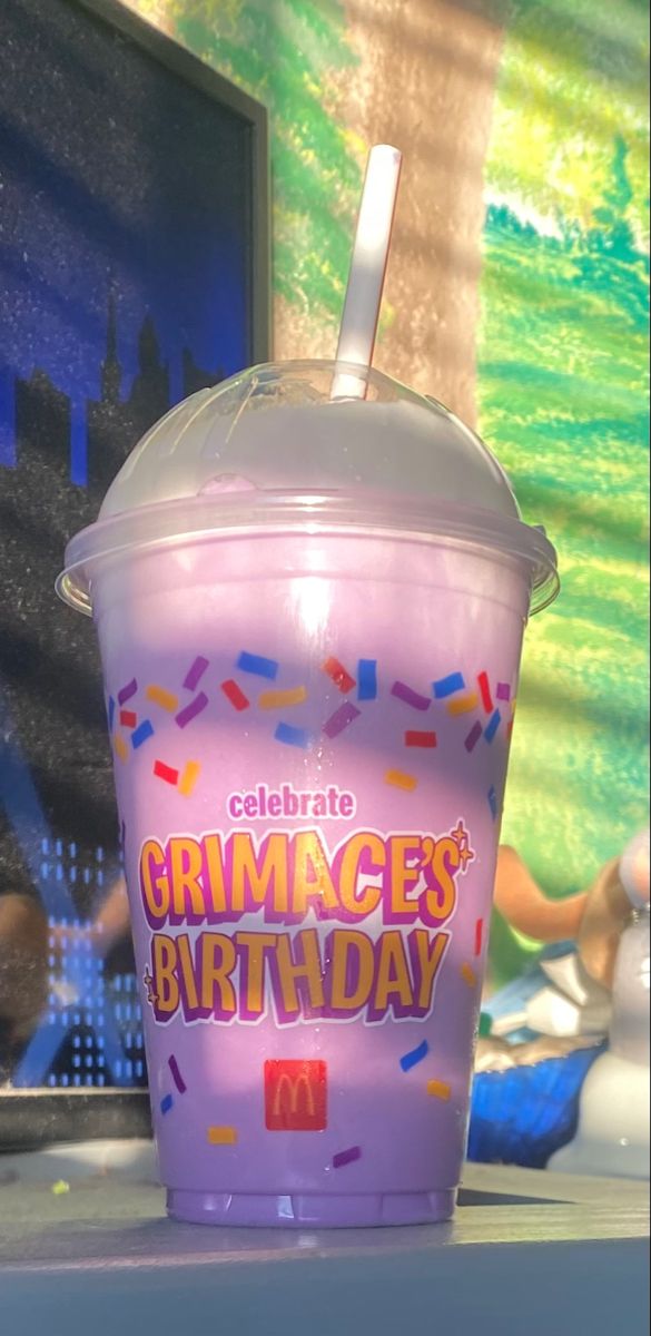 a purple cup with sprinkles and a straw in it sitting on a table