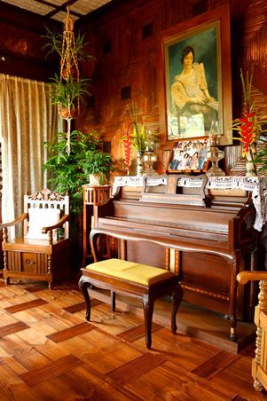 an old piano is in the middle of a room with wood paneling and paintings on the walls