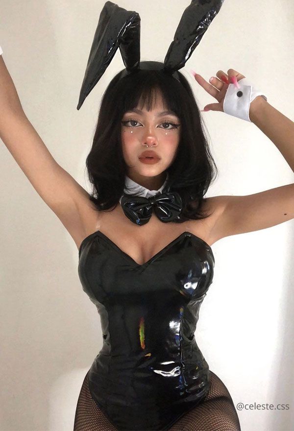 a woman dressed in bunny ears and latex is holding her hands up to the side