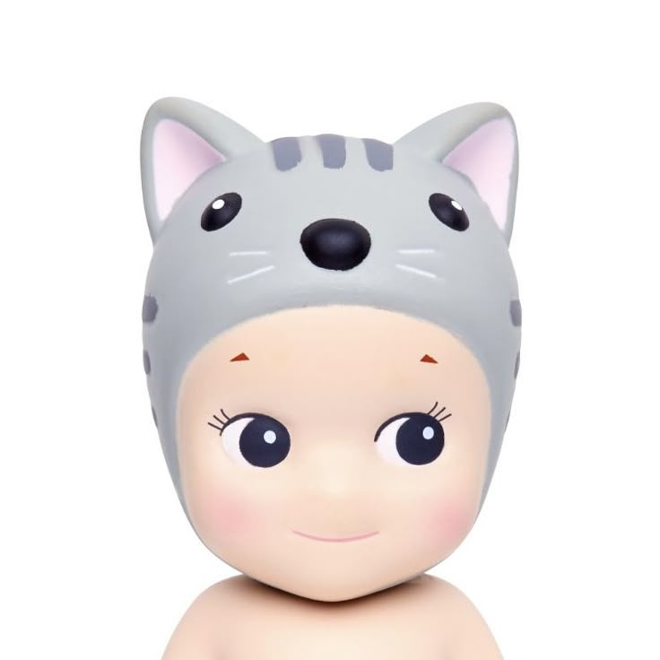 a small doll with a cat hat on top of it's head, sitting in front of a white background