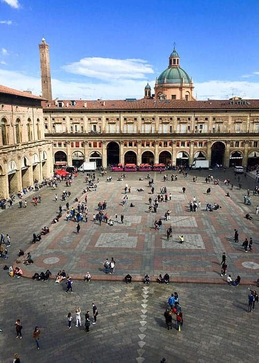 many people are gathered in the courtyard of an old building with large tiles on it