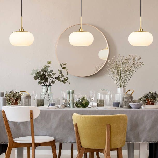 a dining room table with two chairs and a round mirror on the wall