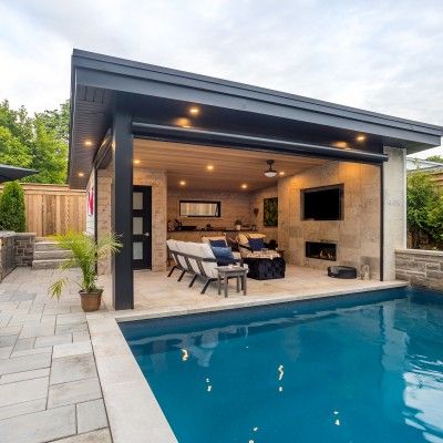 a backyard with a pool, patio and dining table next to an outdoor living area