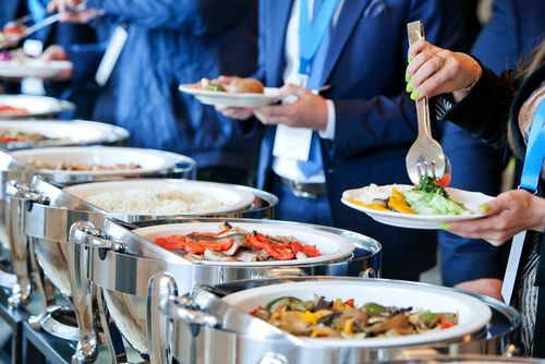 several people are serving themselves food at a buffet line up to be served on plates