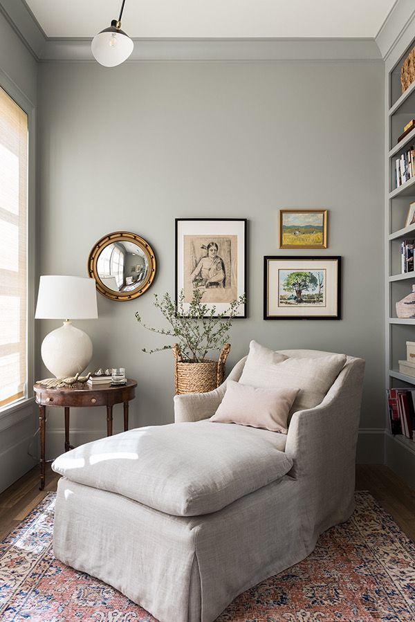 a living room with a chair, ottoman and bookshelf on the wall next to a window