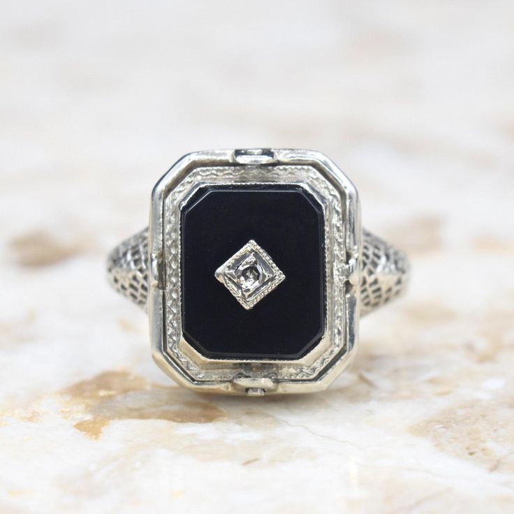 Antique 14k white gold Art Deco era flip ring. One side has a carved shell cameo. The other, an onyx stone set with a small diamond. The filigree setting has blossom details on the shoulders and along the band.  Era: Art Deco c.1920 Markings: 14k PATENTED  Materials: 14k white gold, shell, onyx, diamond  Ring Size: 6.5 (Comes with one free resizing by our jeweler) Weight: 3.1 grams Face measures 14mm x 12mm Condition: Excellent antique condition with minor wear from age  Shipping is free in the United States  Follow us on Instagram @LUXXORVintage White Gold Onyx Ring For Anniversary, Elegant Black Hallmarked Enamel Ring, Classic Engraved Enamel Ring For Formal Occasions, Elegant Black Engraved Ring For Anniversary, Anniversary White Gold Rings With Black Enamel, Formal Black Engraved Ring, Elegant Formal Onyx Signet Ring, Anniversary Onyx Diamond Ring With Polished Finish, Elegant Black Enamel Anniversary Ring