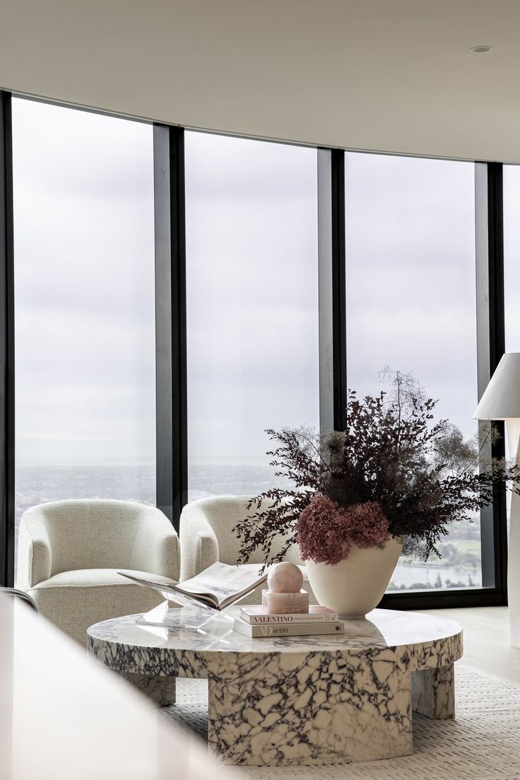 a living room filled with furniture and large windows overlooking the cityscape in the distance