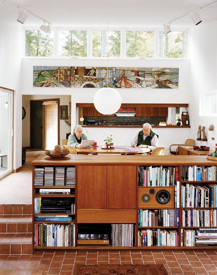 two people sitting at a counter in a room with bookshelves