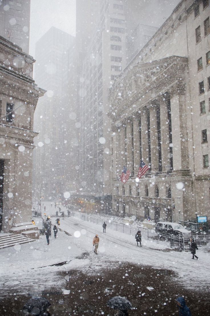 people walking in the snow on a city street