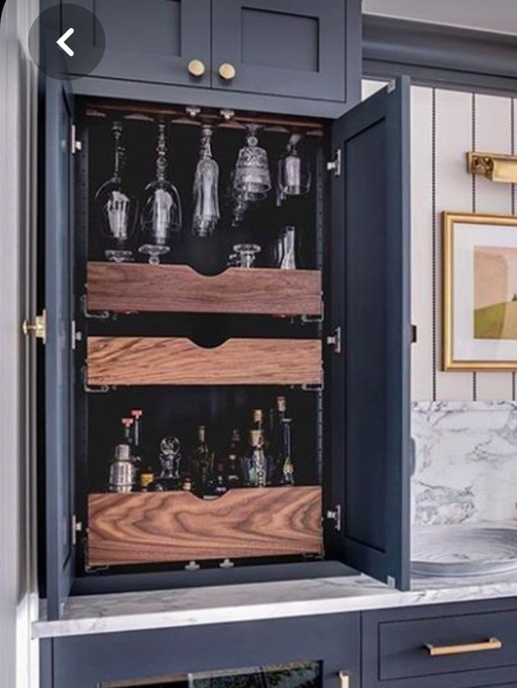 an open cabinet with wine glasses and liquor bottles in it