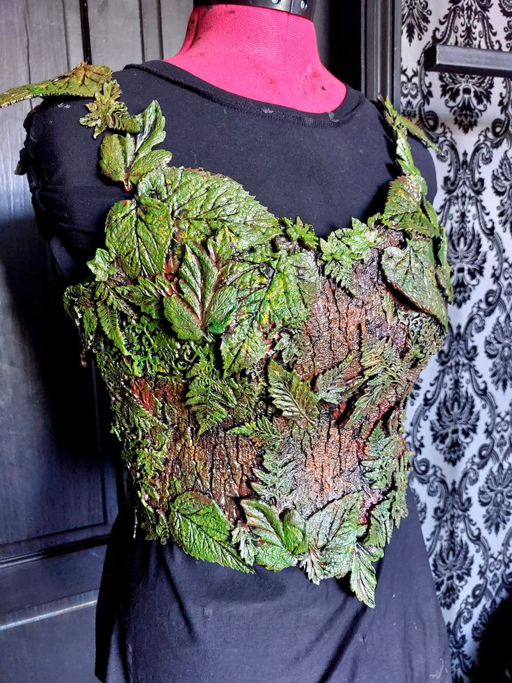 a black dress with green leaves on it and a pink top that is made out of fabric