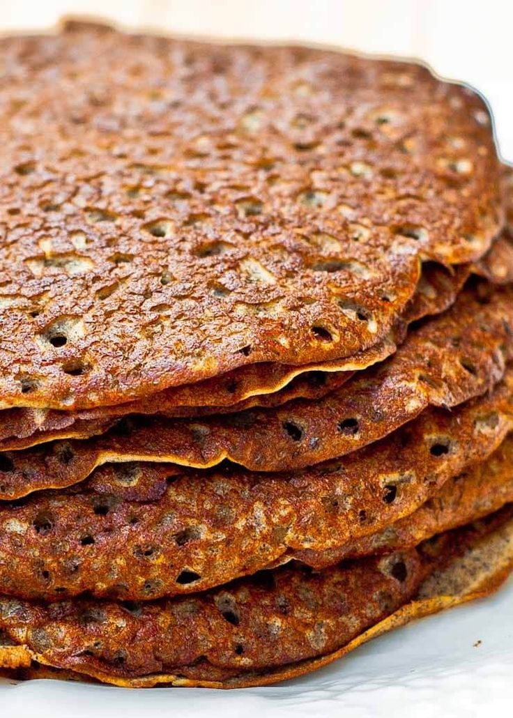 a stack of flatbreads sitting on top of a white plate covered in syrup