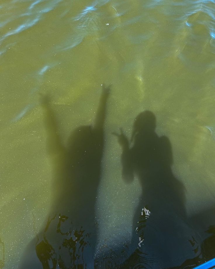 two people standing in the water with their hands up