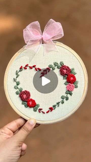 someone is holding up a cross stitch ornament with roses in the shape of a heart