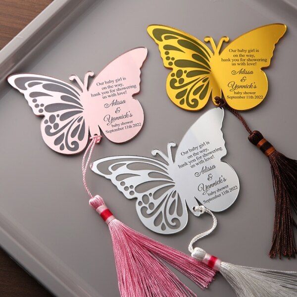 three butterfly shaped tags with tassels on a tray