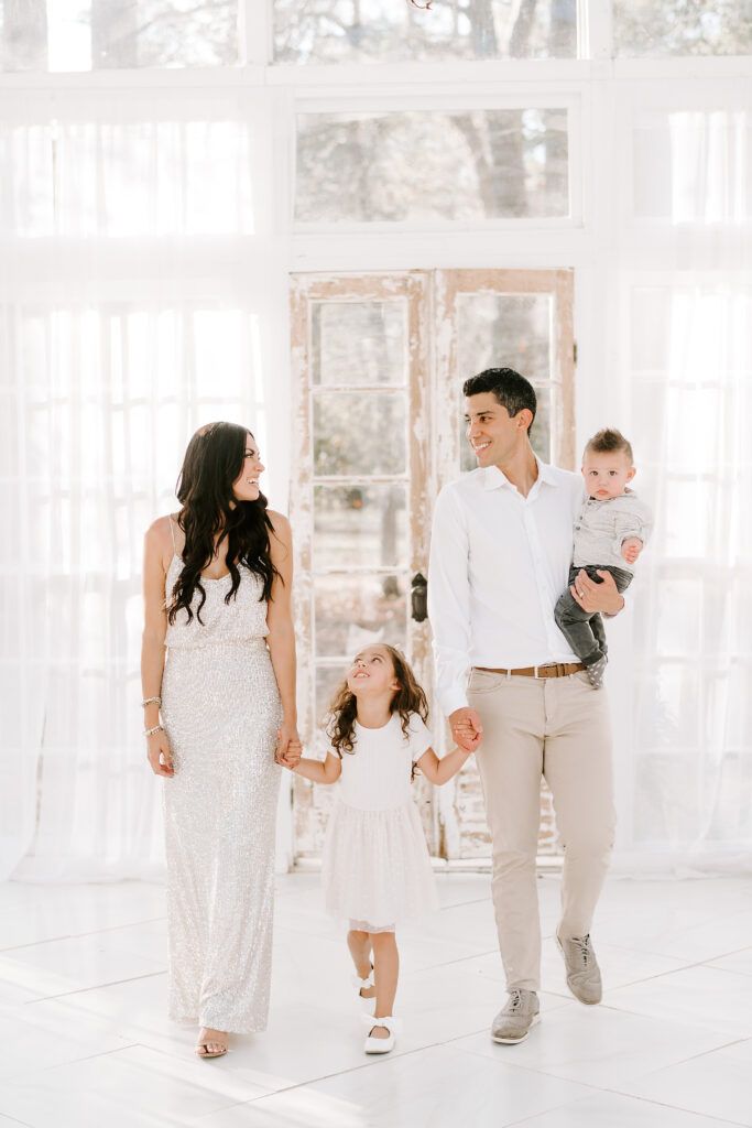 a man and woman holding hands while walking with their baby girl in front of them