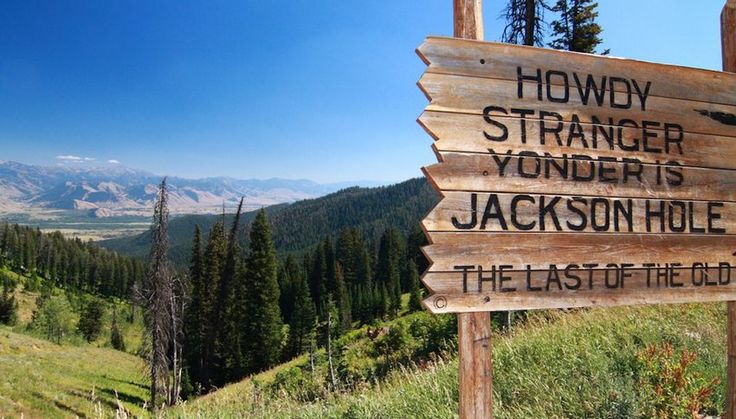 a wooden sign on the side of a mountain pointing to two different places in the distance