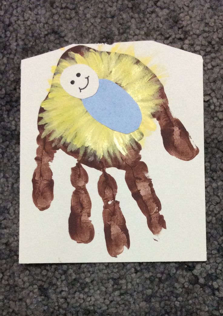 a child's handprint with a yellow and blue bird on it, sitting on the ground