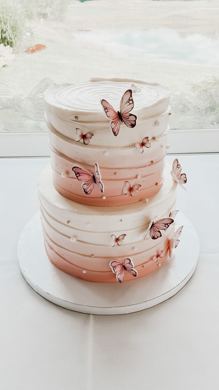 a three tiered cake with pink butterflies on it