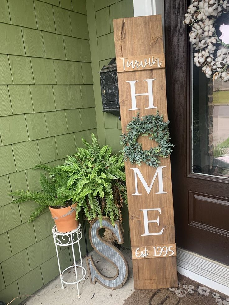 a wooden sign sitting next to a potted plant on top of a door sill