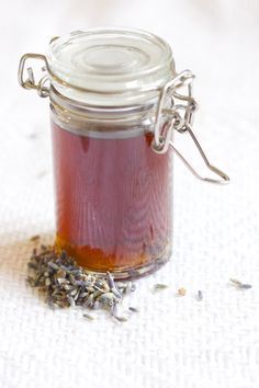 a jar filled with pink liquid sitting on top of a white table covered in silver flakes