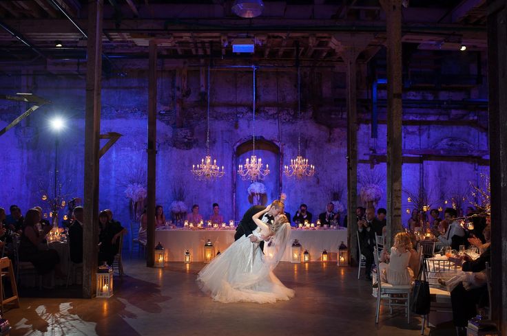 a bride and groom dance at their wedding reception in an old building with chandeliers