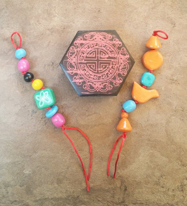 an assortment of colorful beads and necklaces laying on the ground next to a box