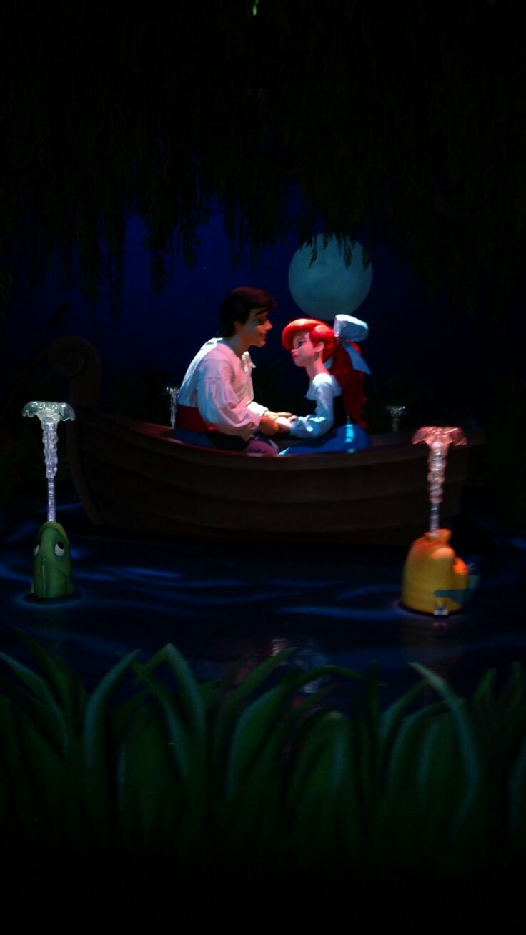 two people in a boat on the water at night with lights and decorations around them