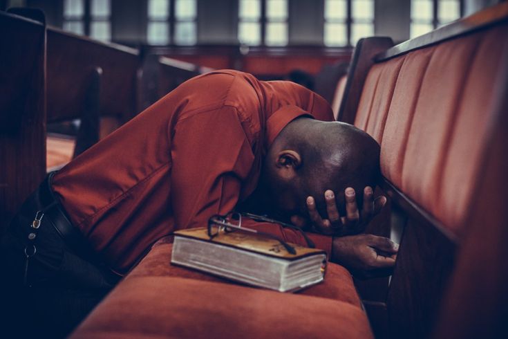 a man is sleeping on a bench with his head in the back of a chair