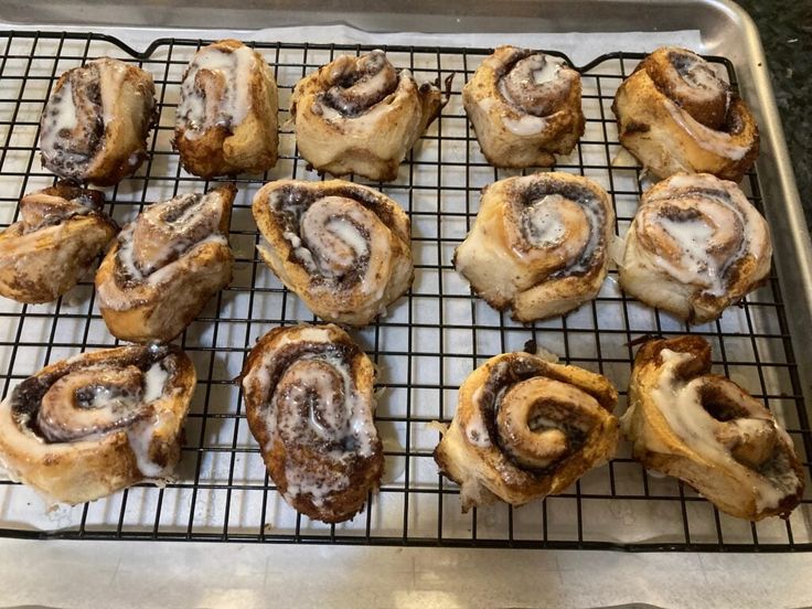 there are many cinnamon rolls on the cooling rack