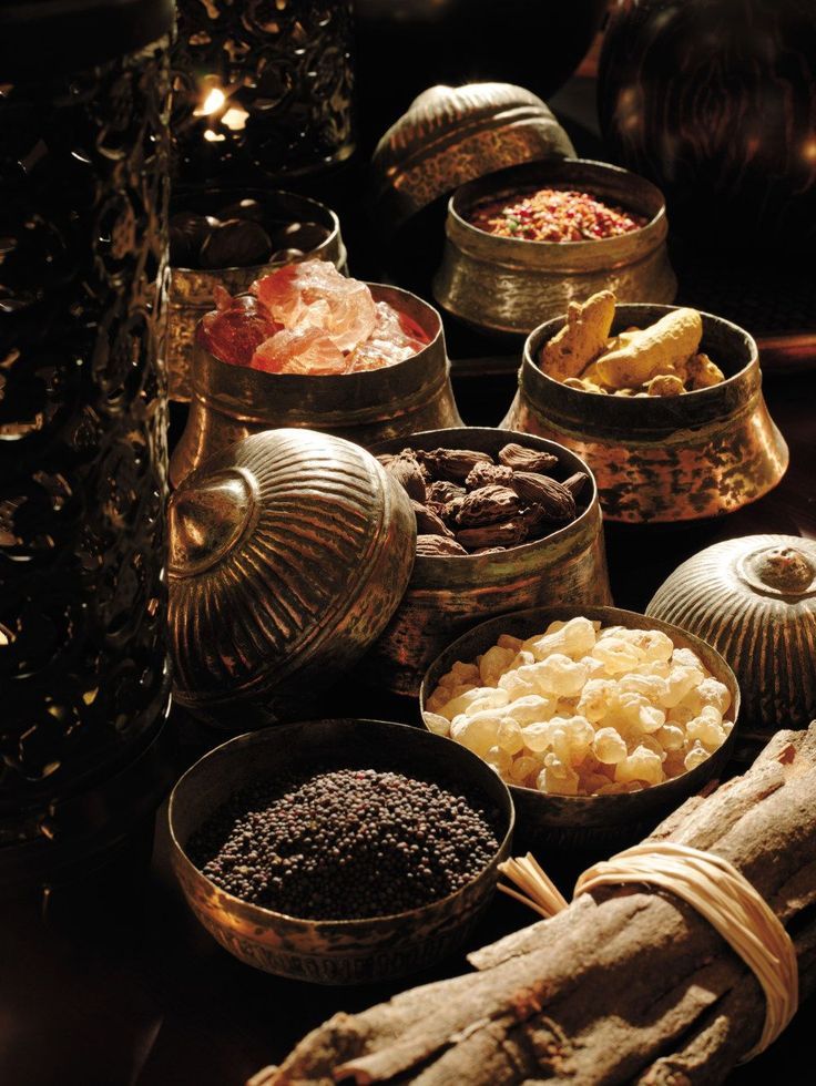 an assortment of different types of food in metal bowls on a table with candles and decorations