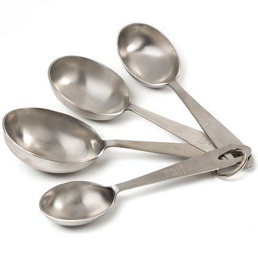 four spoons are arranged in a row on a white surface