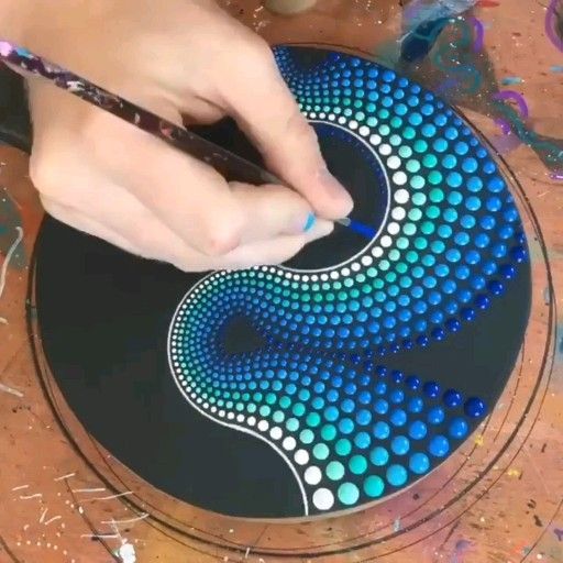 a person is using a pen to draw a design on a glass plate with circles