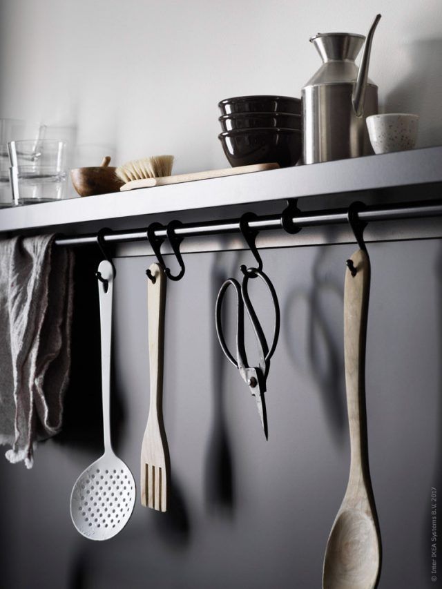 kitchen utensils hanging on the wall with pots and pans in the background