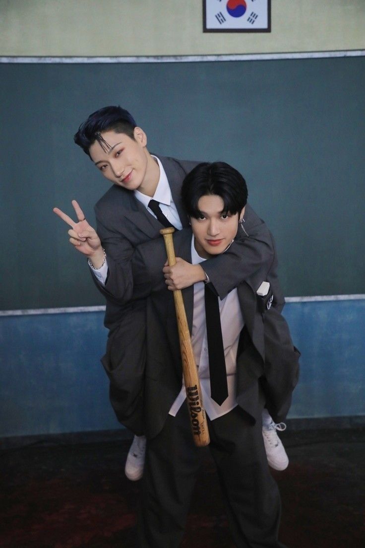 two men in suits and ties are posing for the camera with one holding a baseball bat