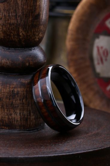 a wooden ring sitting on top of a table next to a sign that says whiskey barrel men's wedding band