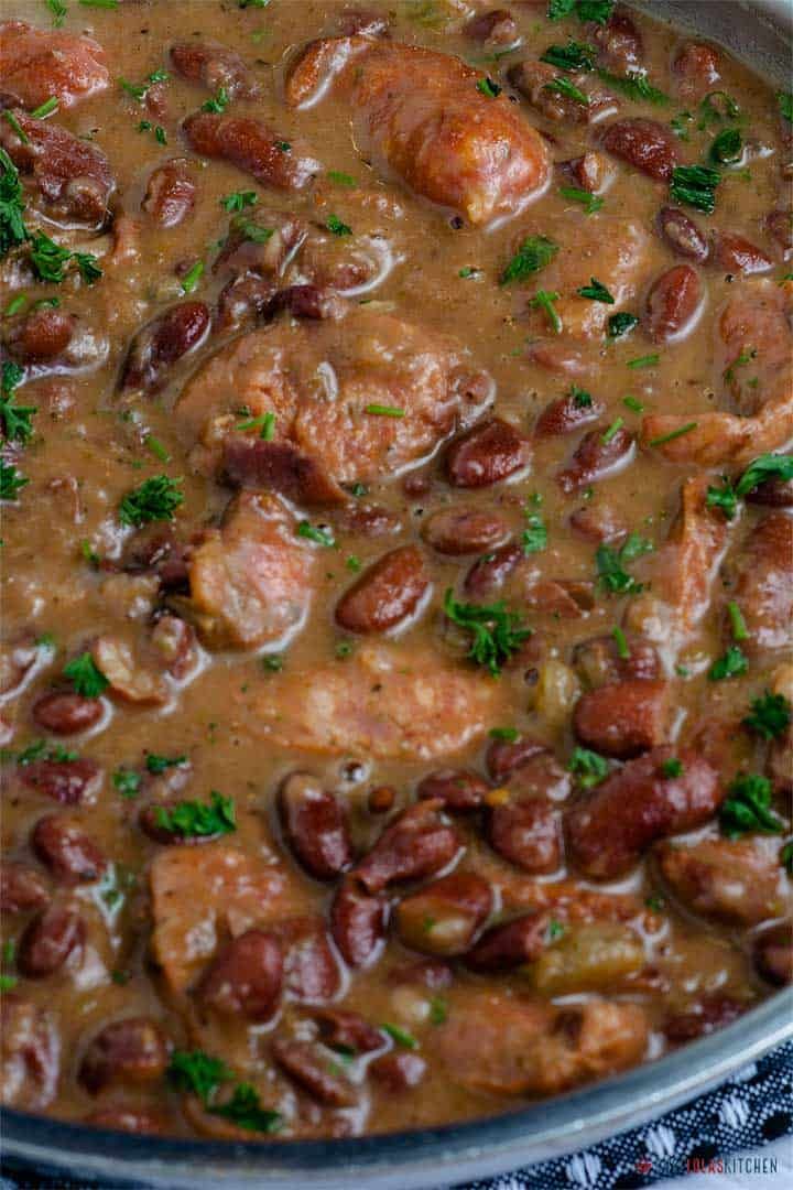 a pan filled with meat and beans covered in gravy, garnished with parsley