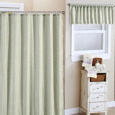 a bathroom with a shower curtain next to a window and a dresser in front of it