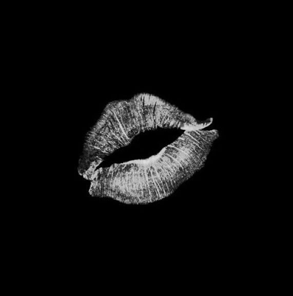 a black and white photo of a woman's lips in the dark with her tongue out