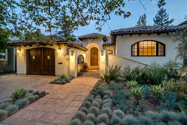 a house that is lit up with lights and plants in front of the entrance to it