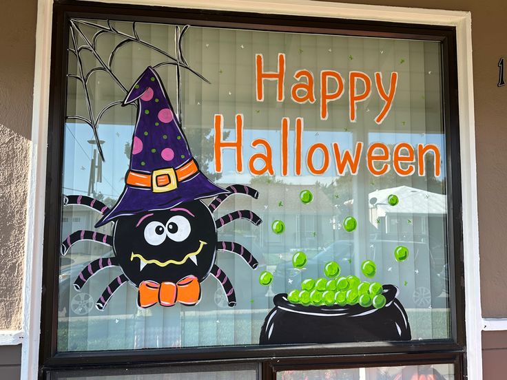 a happy halloween sign in the window of a store front with a witch hat and caulder