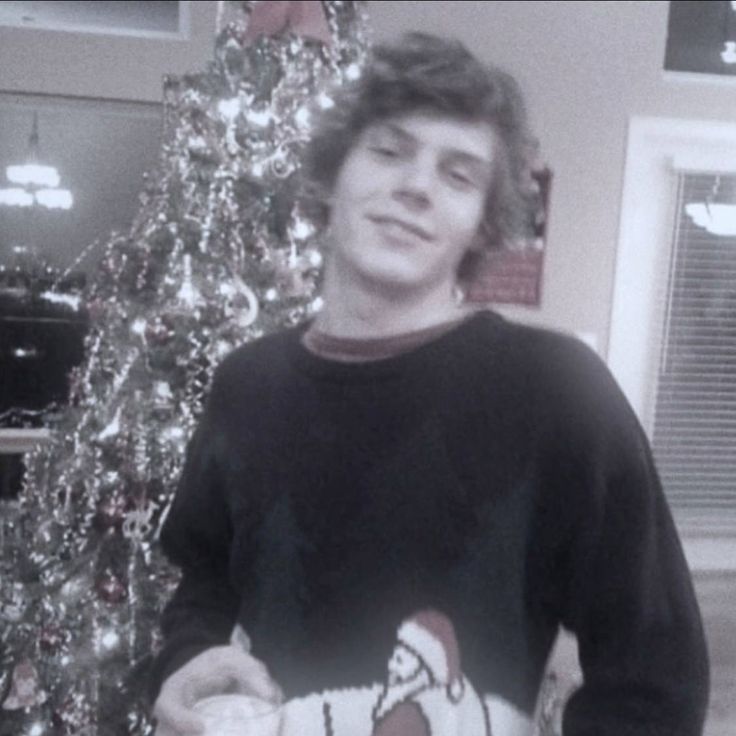 a man standing in front of a christmas tree